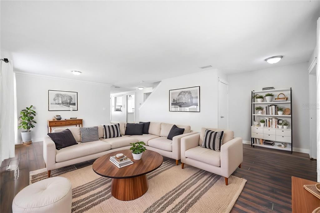A bright living room features a beige sectional sofa, a round wooden coffee table, and shelving — 14026 JACOBSON DRIVE, ODESSA, FL
