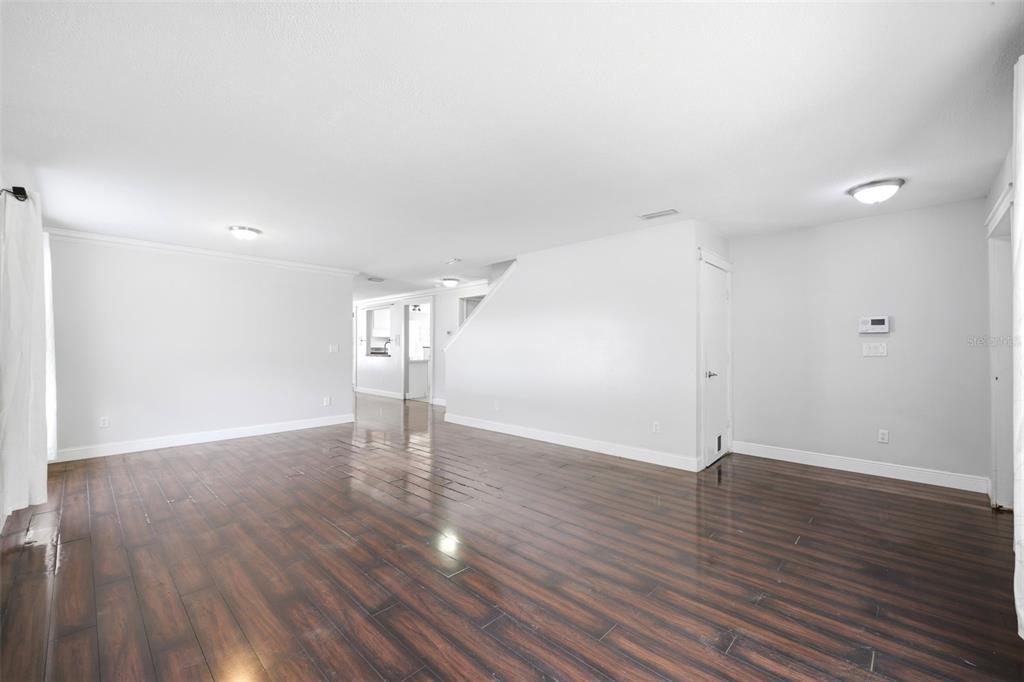 An empty living room features dark wood-look flooring, white walls, and recessed ceiling lighting — 14026 JACOBSON DRIVE, ODESSA, FL