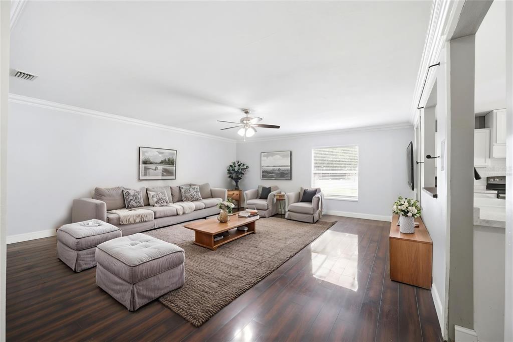 A living room features a large sectional sofa, two armchairs, and dark wood flooring — 14026 JACOBSON DRIVE, ODESSA, FL