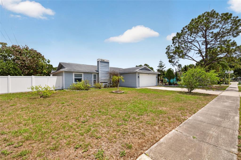 A single-story house with light blue siding, a white garage door, and a front lawn — 11207 FIRESIDE DRIVE, TAMPA, FL