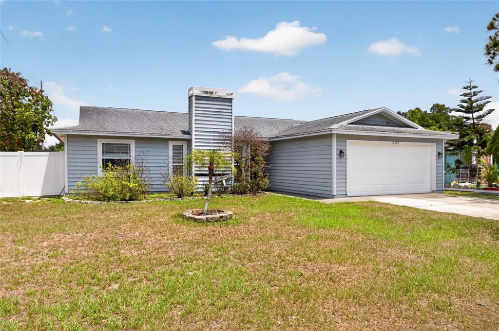 A single-story house with light blue siding, a white garage door, and a front lawn — 11207 FIRESIDE DRIVE, TAMPA, FL