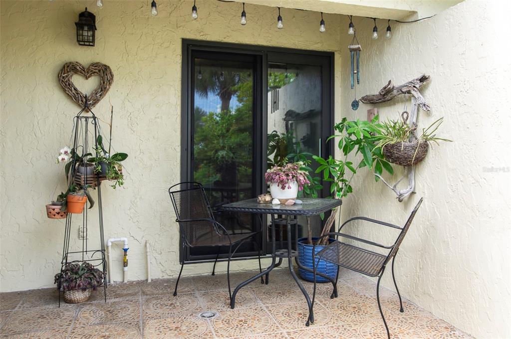 A patio features a small table with two chairs, potted plants, and string lights — 10152 REGAL DRIVE, LARGO, FL