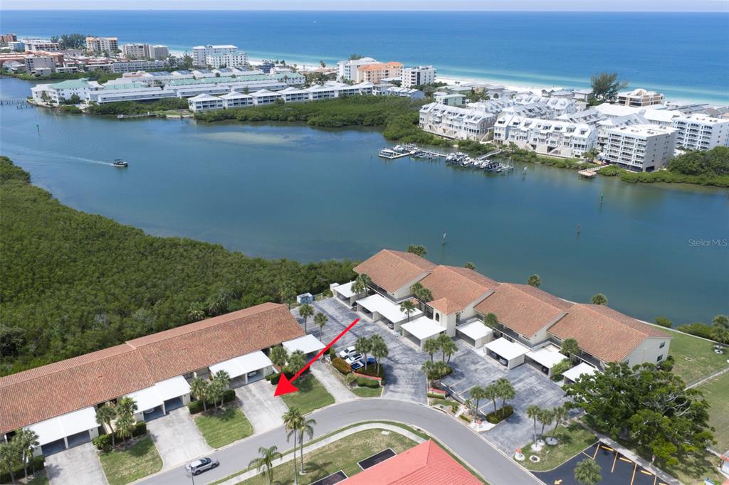 An aerial view shows a residential complex with covered parking spaces near a bay — 10152 REGAL DRIVE, LARGO, FL