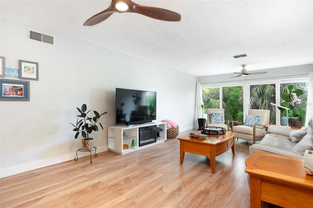 A living room features wood-look flooring, a television console, and a large sliding glass door — 10152 REGAL DRIVE, LARGO, FL