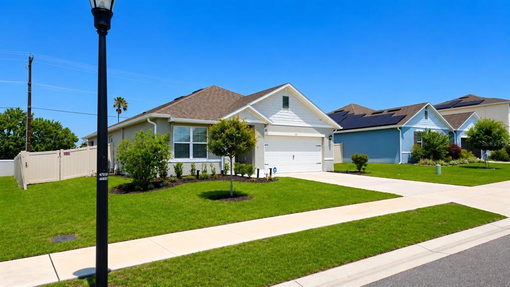 A single-story suburban house with a two-car garage, tan siding, and a manicured lawn — 127 AUBURN GROVE BOULEVARD, AUBURNDALE, FL