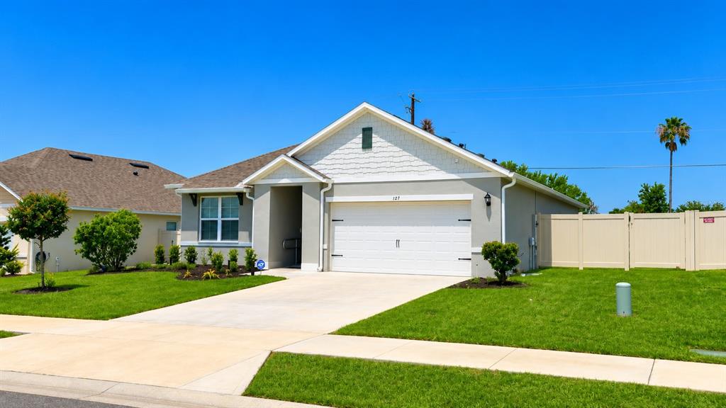 A single-story house with a white garage, gray siding, and a tan vinyl fence — 127 AUBURN GROVE BOULEVARD, AUBURNDALE, FL