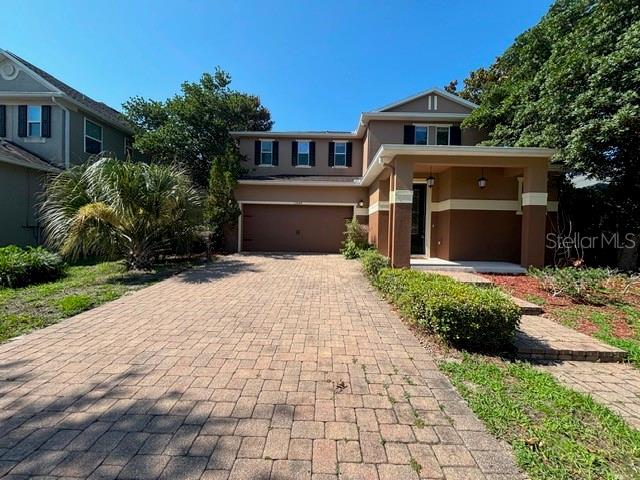 A two-story suburban house features a brick driveway, a garage, and a covered front porch — 11844 CHATEAUBRIAND AVENUE, ORLANDO, FL