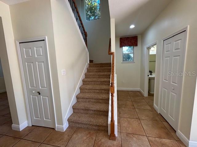 An interior view shows a carpeted staircase between two white doors and tile flooring — 11844 CHATEAUBRIAND AVENUE, ORLANDO, FL