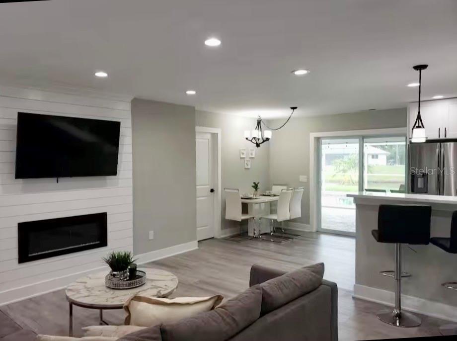 A living room with a shiplap fireplace wall, dining area, and kitchen breakfast bar — 1385 HARMONY DRIVE, PORT CHARLOTTE, FL