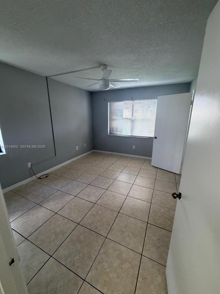 An empty bedroom features gray walls, a ceiling fan, and light-colored tile flooring — 20825 NE 8th Ct # 19, Miami FL 33179, MIAMI, FL