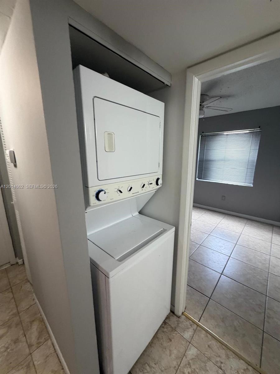 A stacked white washer and dryer unit sits in a tiled laundry closet — 20825 NE 8th Ct # 19, Miami FL 33179, MIAMI, FL