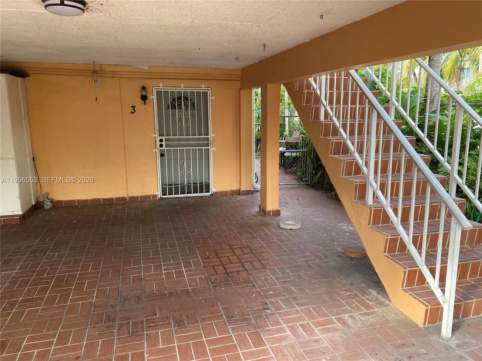 A covered patio features brick flooring, a white security door, and an outdoor staircase — 1051 SW 3rd St # 3, Miami FL 33130, MIAMI, FL