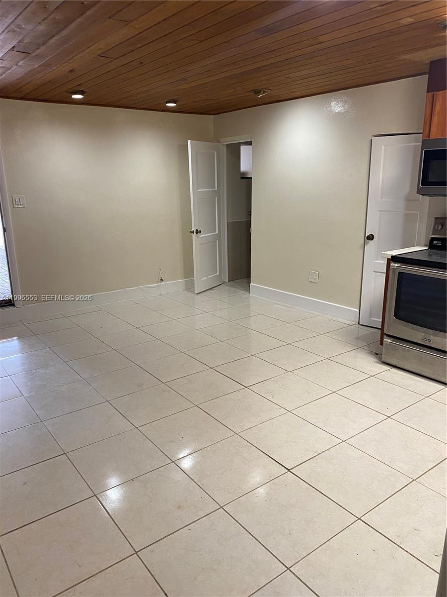 A kitchen area features light-colored tile flooring, beige walls, and a wood-paneled ceiling — 1051 SW 3rd St # 3, Miami FL 33130, MIAMI, FL