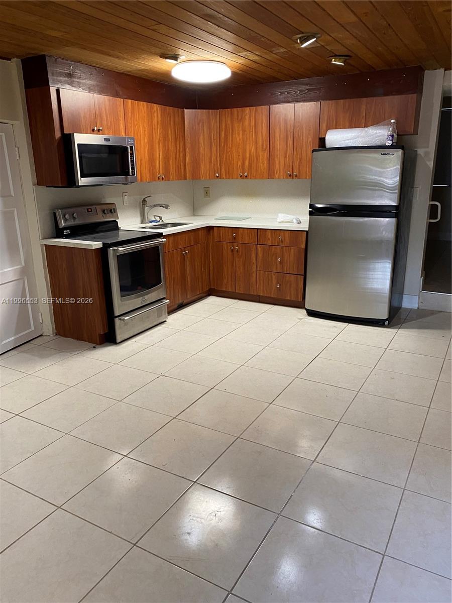 A kitchen features wood-grain cabinets, stainless steel appliances, and a wood-paneled ceiling — 1051 SW 3rd St # 3, Miami FL 33130, MIAMI, FL
