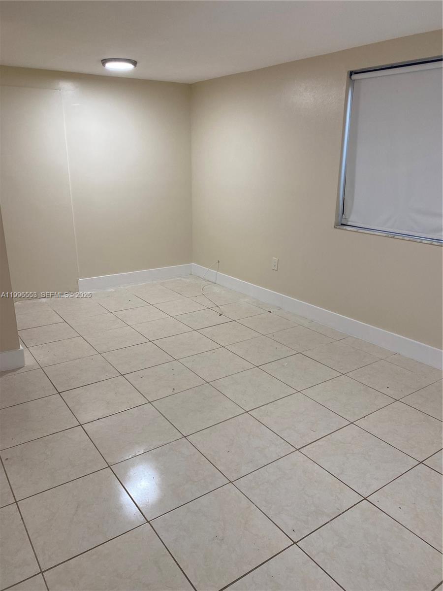 An empty room features beige walls, white baseboards, and light-colored square floor tiles — 1051 SW 3rd St # 3, Miami FL 33130, MIAMI, FL