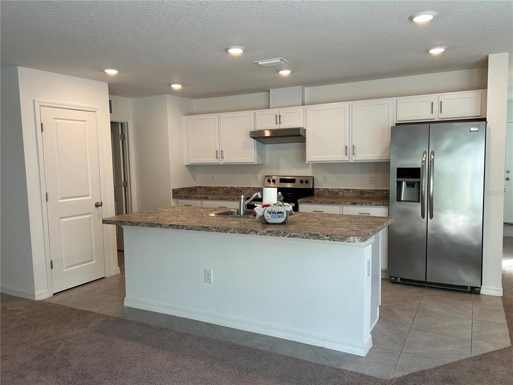 A kitchen features white cabinets, a large island with a sink, and stainless steel appliances — 2706 89TH STREET CIRCLE E, PALMETTO, FL
