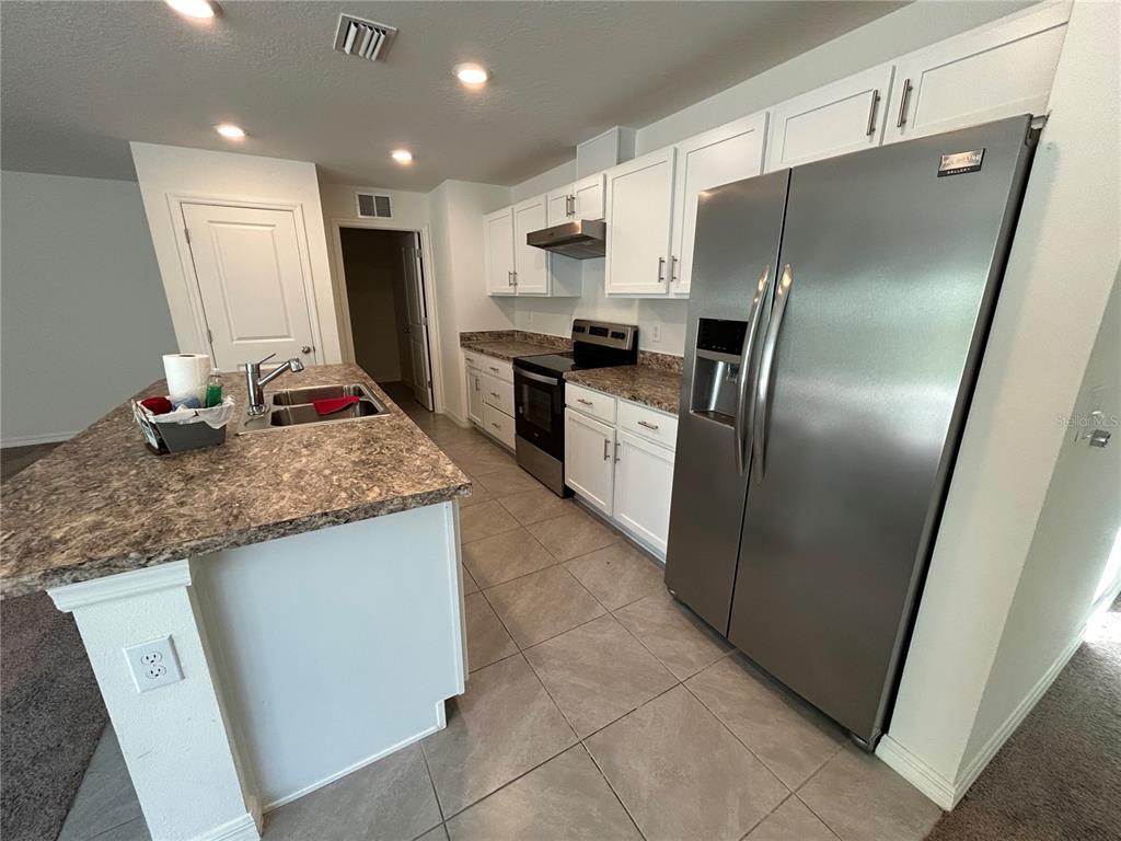 A kitchen features white cabinets, stainless steel appliances, a kitchen island, and brown countertops — 2706 89TH STREET CIRCLE E, PALMETTO, FL