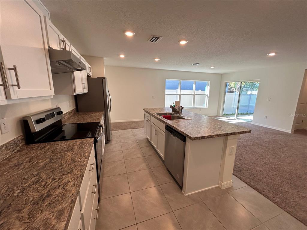 A kitchen with white cabinets, granite-look countertops, and a center island with a dishwasher — 2706 89TH STREET CIRCLE E, PALMETTO, FL