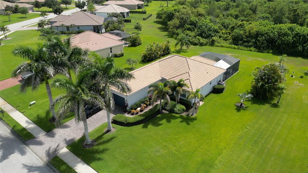 An aerial view shows a single-story house with a tiled roof, pool enclosure, and landscaping — 625 148TH COURT NE, BRADENTON, FL