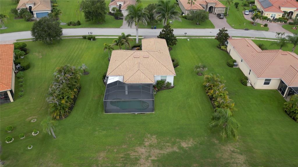 An aerial view shows a house with a tiled roof, a screened pool, and landscaping — 625 148TH COURT NE, BRADENTON, FL