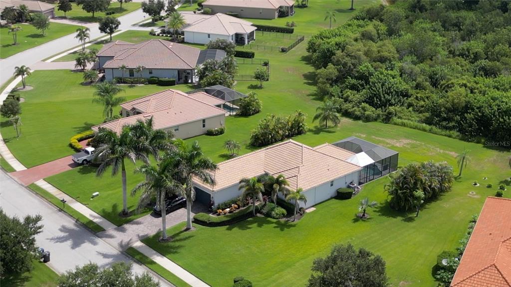 An aerial view shows several suburban houses with tiled roofs, swimming pools, and manicured lawns — 625 148TH COURT NE, BRADENTON, FL
