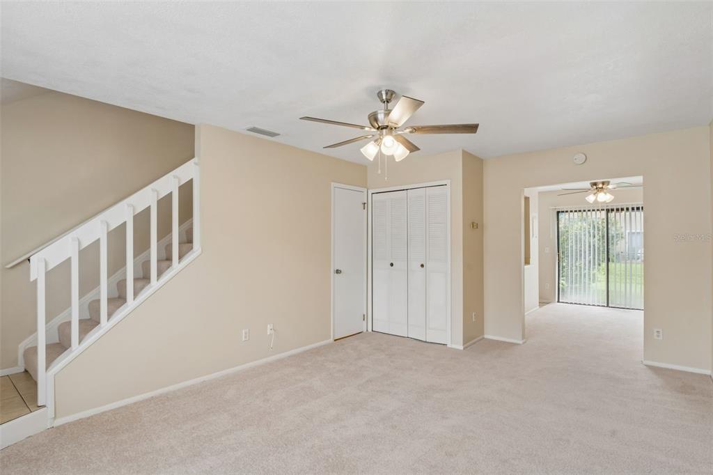 A carpeted living room features a staircase with white railings, a ceiling fan, and closets — 1307 PARK VILLA PLACE, WINTER SPRINGS, FL