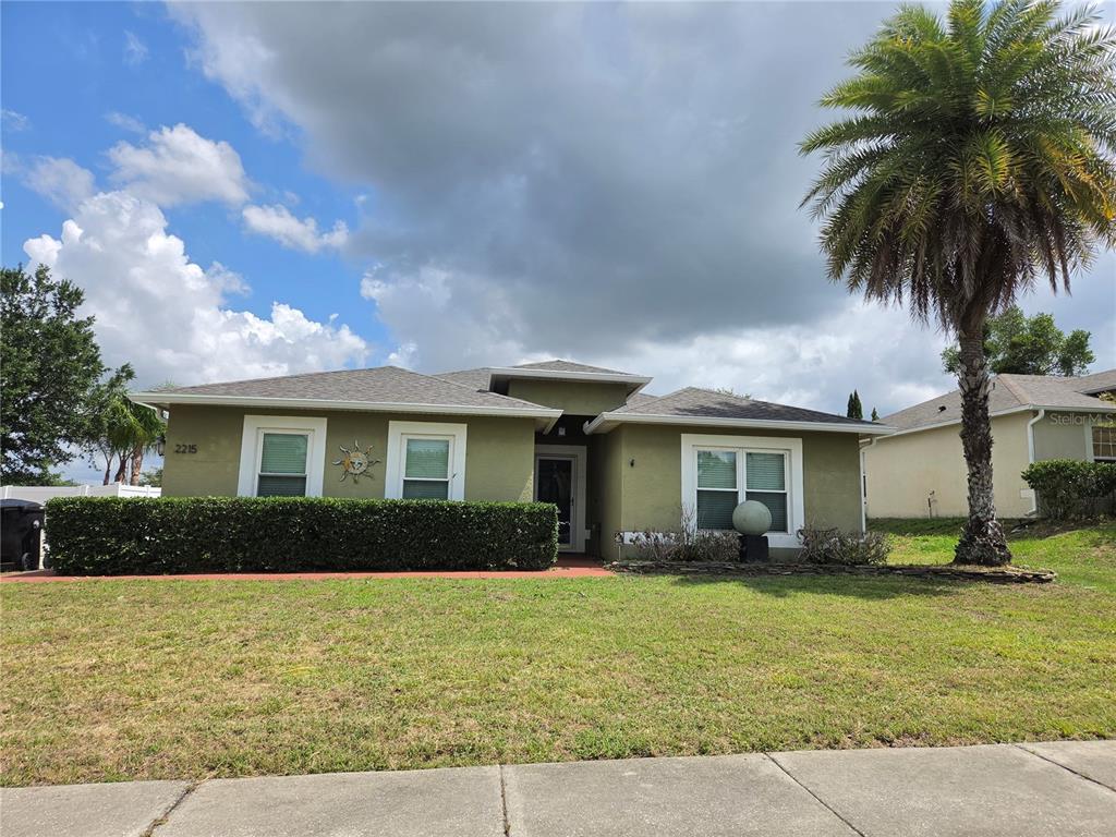 A single-story house with a green exterior, a front hedge, and a palm tree — 2215 KINGSCREST CIRCLE, APOPKA, FL