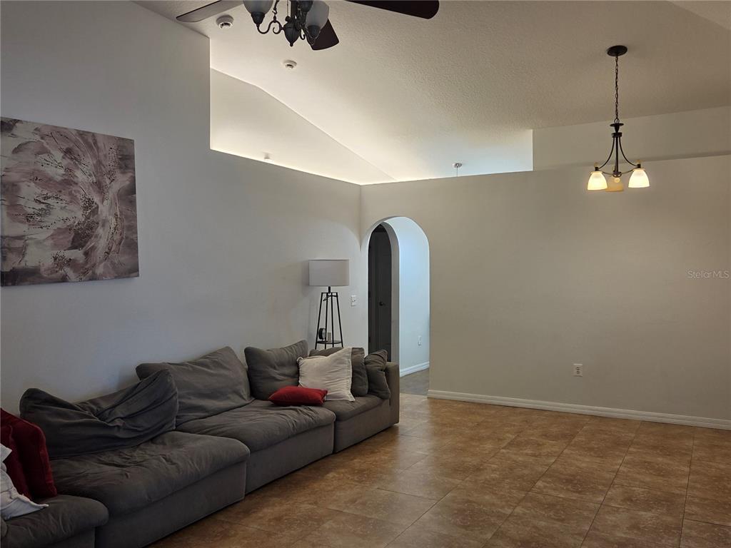 A living room features a large grey sectional sofa, tiled floors, and an arched doorway — 2215 KINGSCREST CIRCLE, APOPKA, FL