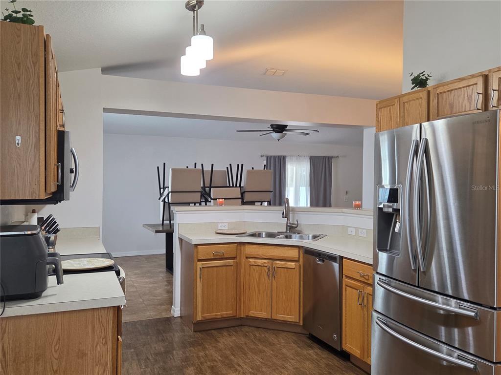 A kitchen with oak cabinets, stainless steel appliances, and a view into the dining area — 2215 KINGSCREST CIRCLE, APOPKA, FL