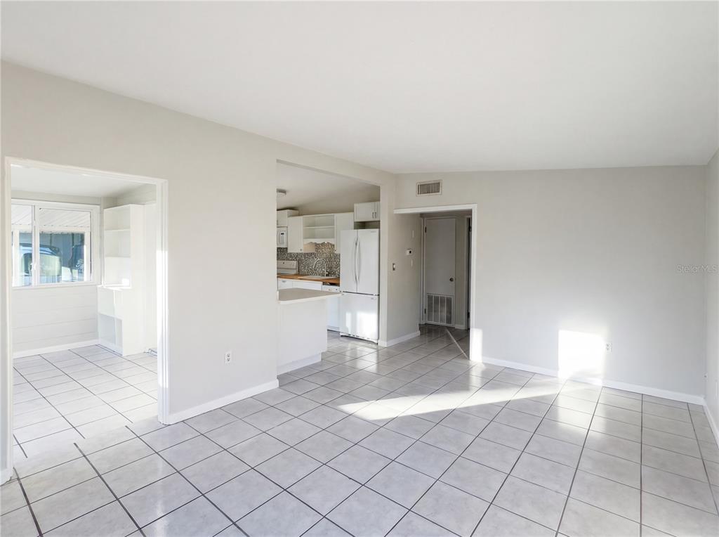 A room with light gray tile flooring, white walls, and an open kitchen area — 911 NEW YORK STREET, EDGEWATER, FL