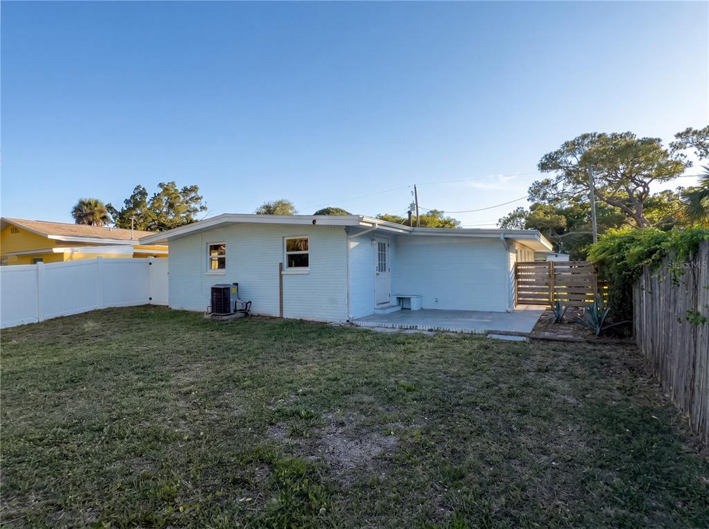 The backyard of a light blue, single-story house with a concrete patio and wooden fence — 911 NEW YORK STREET, EDGEWATER, FL