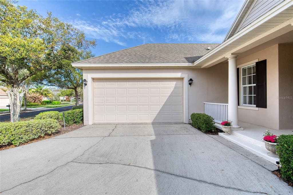A beige house exterior features a two-car garage, a concrete driveway, and a front porch — 314 BELLINGRATH TERRACE, DELAND, FL