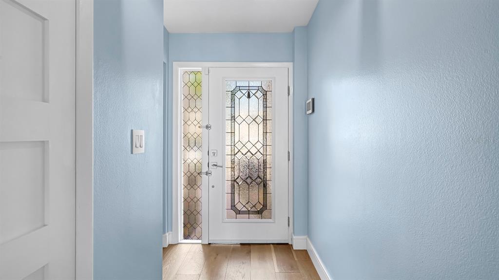 An entryway features light blue walls, hardwood flooring, and a white door with decorative glass — 7 EMERALD COURT, SATELLITE BEACH, FL