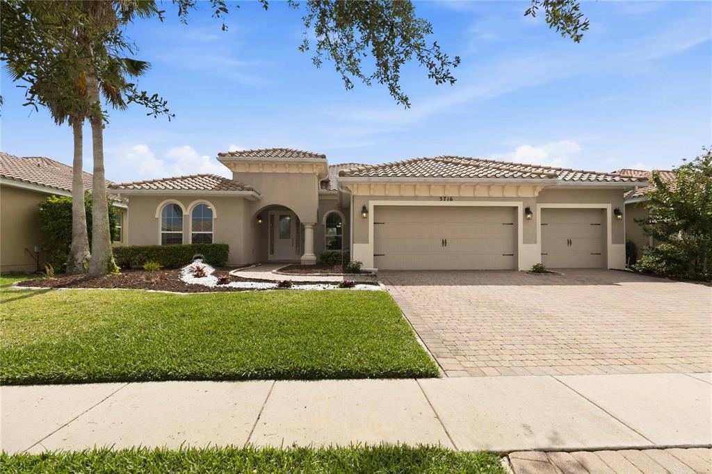 A single-story house with a beige stucco exterior, tile roof, and a three-car garage — 3716 PARADISO CIRCLE, KISSIMMEE, FL