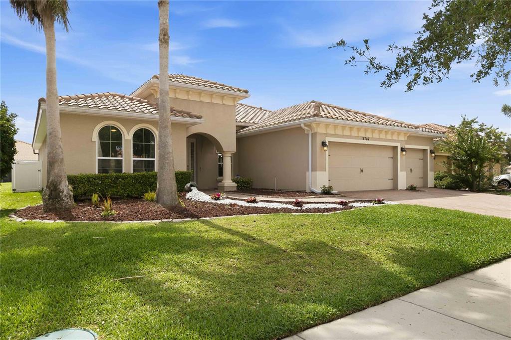 A single-story tan house with a tile roof, arched windows, and a three-car garage — 3716 PARADISO CIRCLE, KISSIMMEE, FL