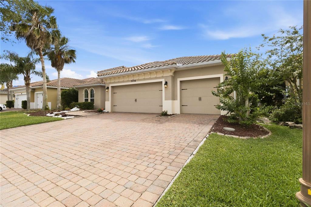 A single-story house with a paved driveway and two garage doors under a tile roof — 3716 PARADISO CIRCLE, KISSIMMEE, FL