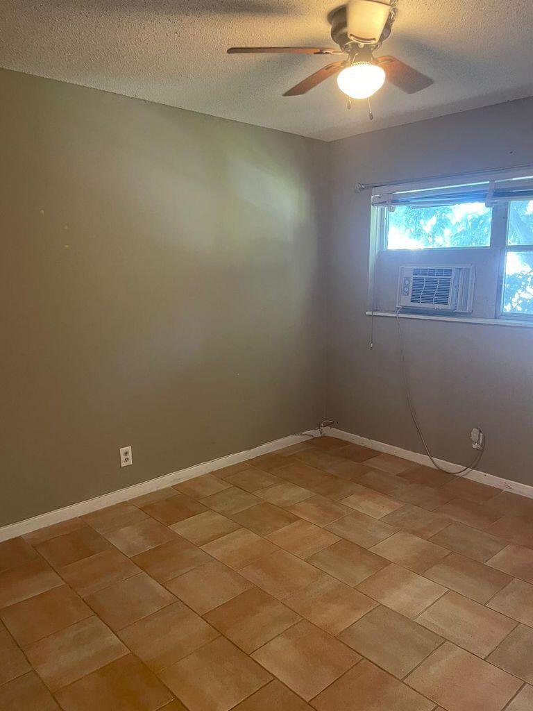 An empty bedroom features light brown tile flooring, gray walls, and a ceiling fan — 702 N L Street # 13, FL 33460, FL