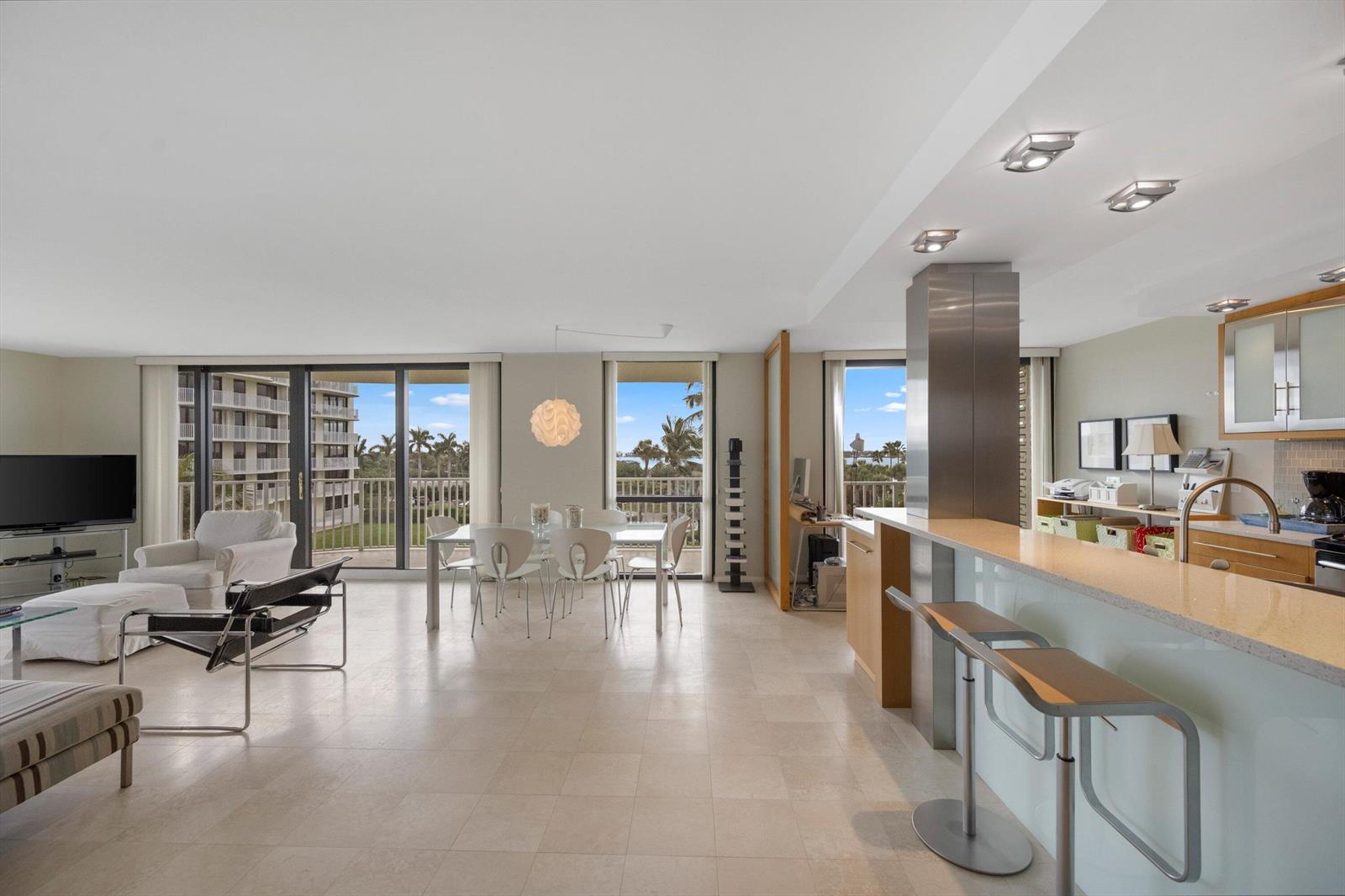 An open-concept living and dining area features tile floors, a kitchen island, and balcony views — 3360 S Ocean Boulevard # I, Palm Beach FL 33480, PALM BEACH, FL