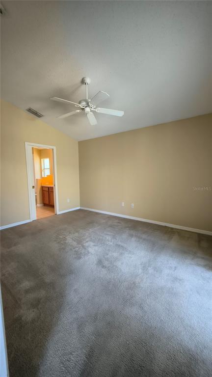 A bedroom with beige walls, gray carpeting, and a white ceiling fan — 16721 S ROLLING GREEN DRIVE S, CLERMONT, FL