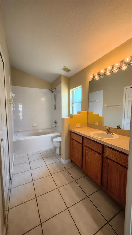 A bathroom features a wooden vanity, a large mirror, a tiled floor, and a tub-shower — 16721 S ROLLING GREEN DRIVE S, CLERMONT, FL