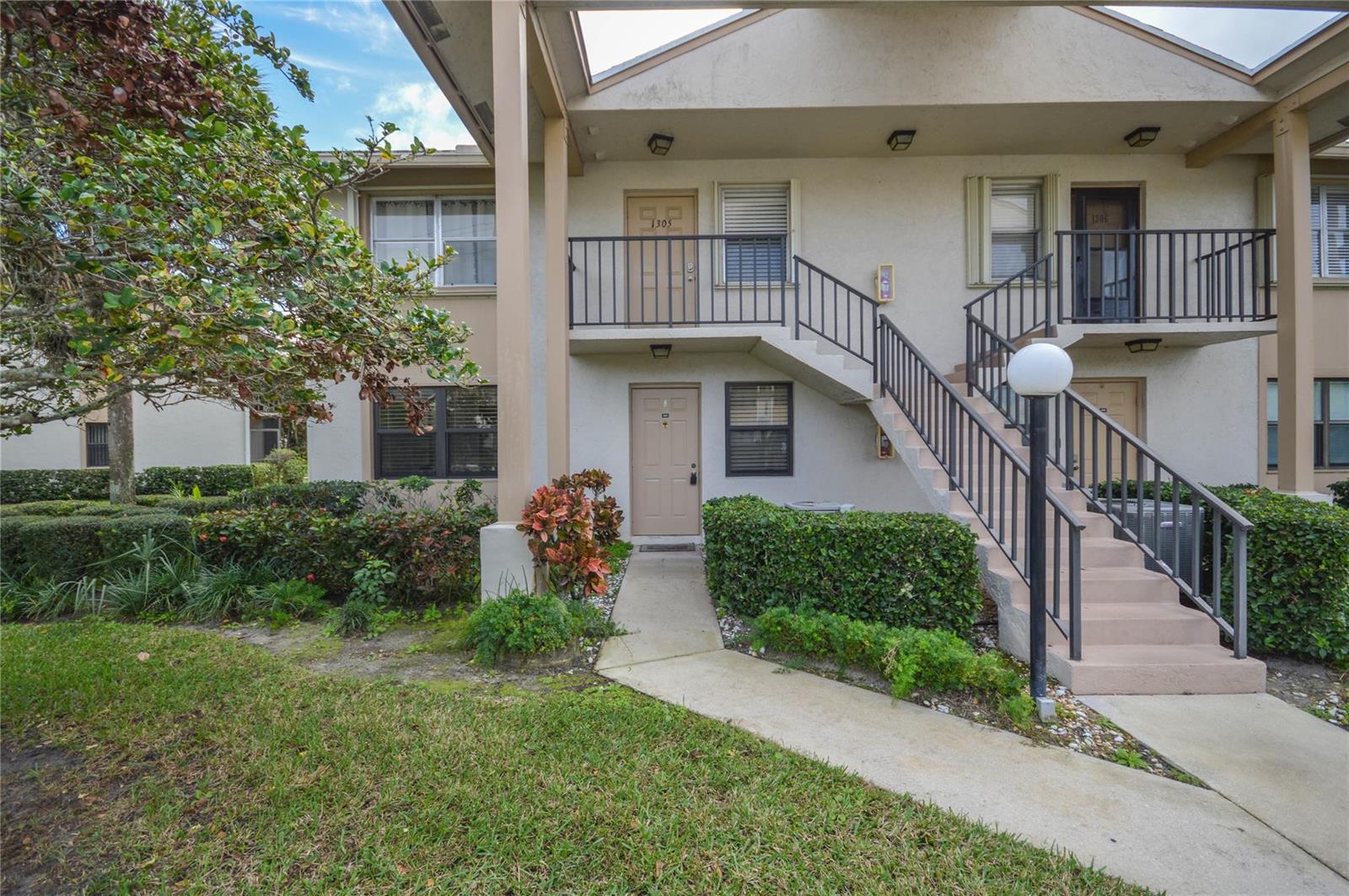 A two-story apartment building exterior features a concrete staircase leading to an upper-level balcony — 3151 SE Aster Lane # 1301, Stuart FL 34994, STUART, FL
