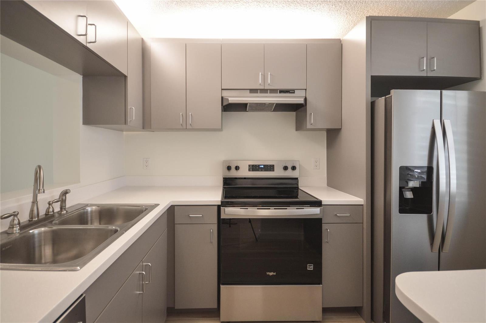 A kitchen features gray cabinets, stainless steel appliances, a double sink, and white countertops — 3151 SE Aster Lane # 1301, Stuart FL 34994, STUART, FL
