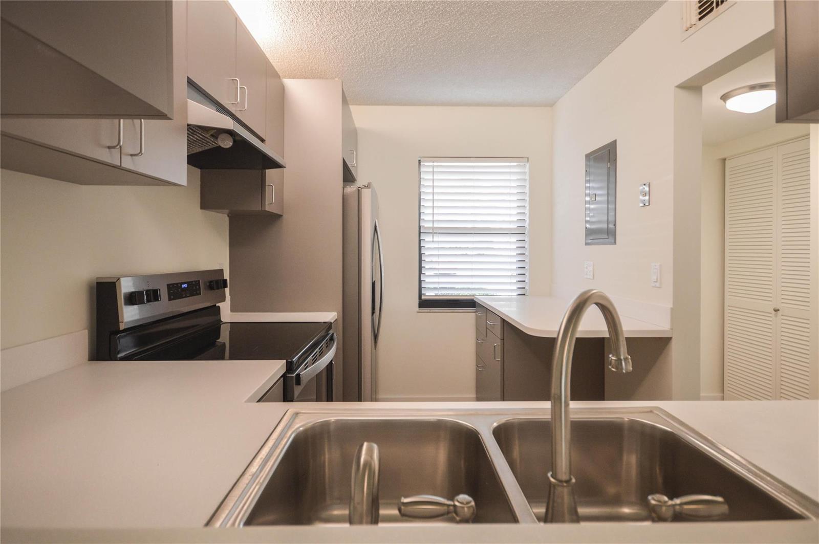 A kitchen features stainless steel appliances, gray cabinets, white countertops, and a double-basin sink — 3151 SE Aster Lane # 1301, Stuart FL 34994, STUART, FL