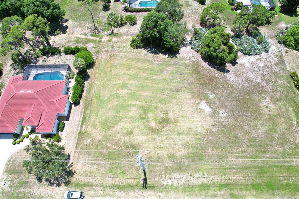 An aerial view shows a vacant, grassy residential lot next to a house with a pool — 4250 CAPE HAZE DRIVE, PLACIDA, FL