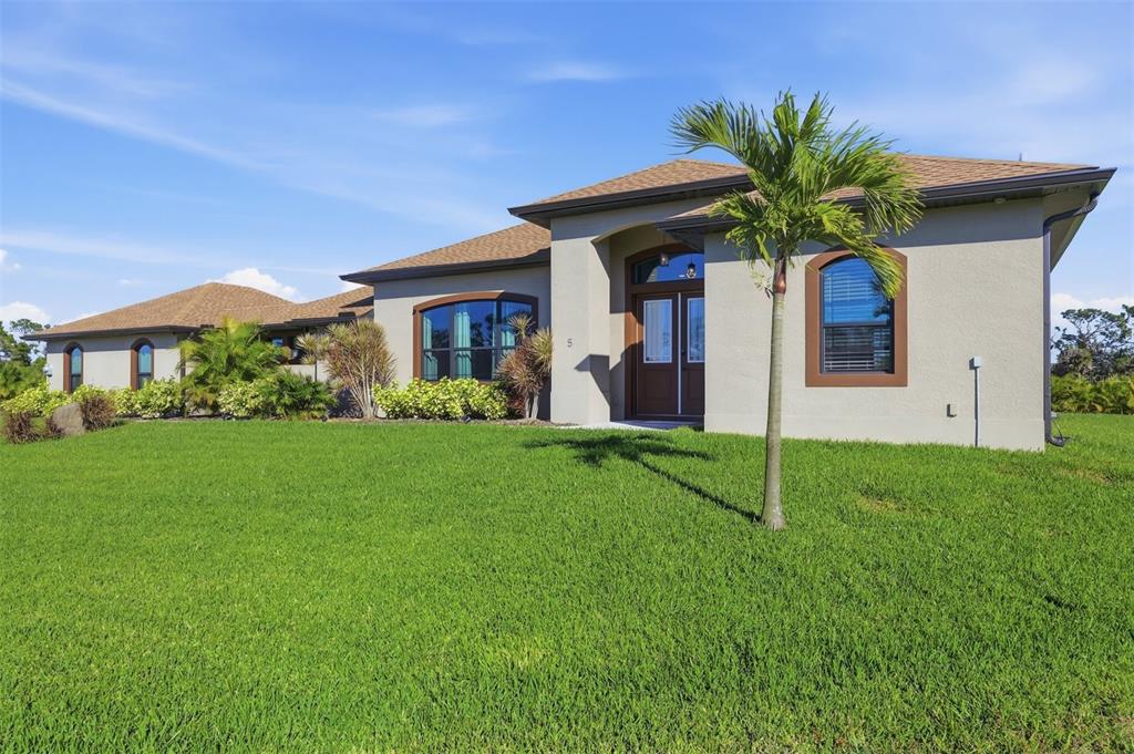 A single-story house with a brown shingled roof, tan stucco exterior, and a concrete driveway — 5 AYE COURT, PLACIDA, FL