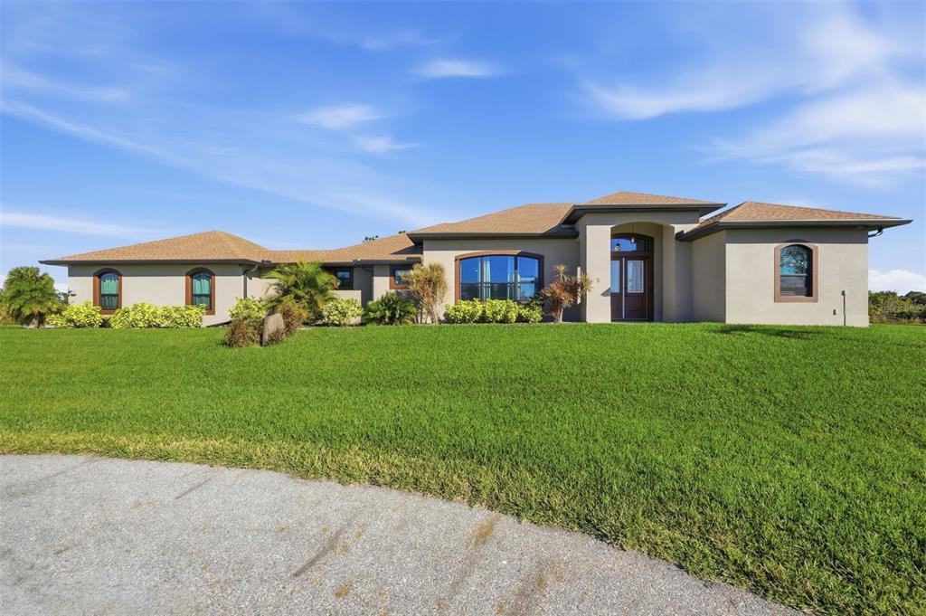 The exterior of a single-story house features a tan stucco facade, arched windows, and a double-door entrance — 5 AYE COURT, PLACIDA, FL