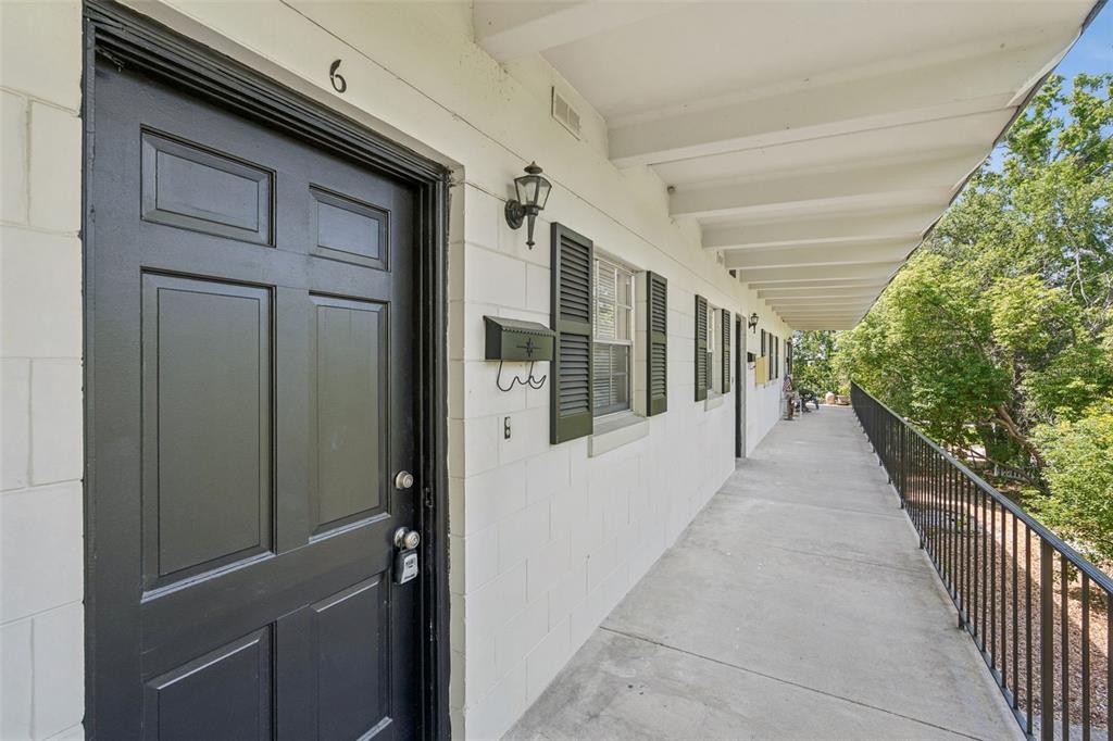 A galley kitchen features white cabinets, granite countertops, stainless steel appliances, and dark blue backsplash — 791 LAKE AVENUE UNIT 6, CLERMONT, FL