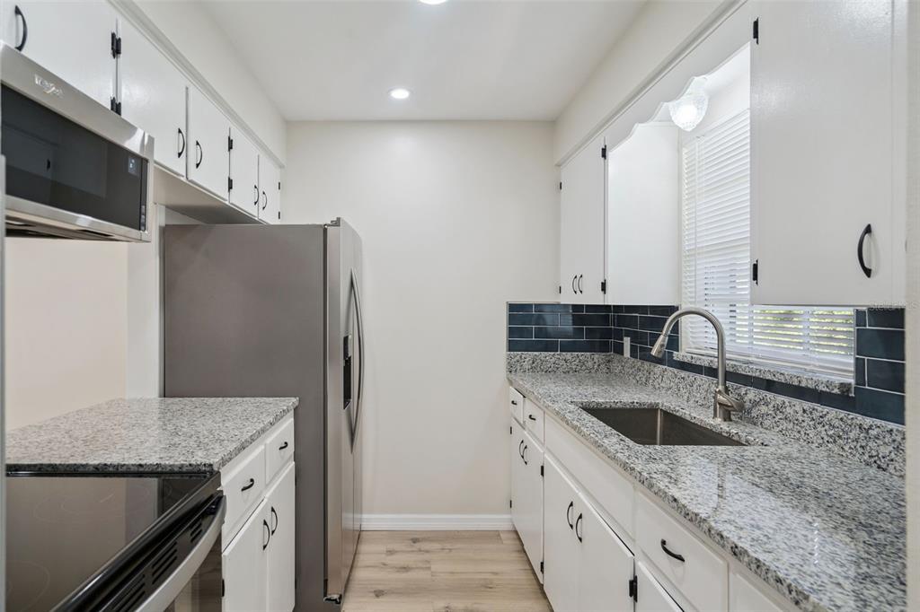 A kitchen features stainless steel appliances, white cabinets, and a granite countertop — 791 LAKE AVENUE UNIT 6, CLERMONT, FL