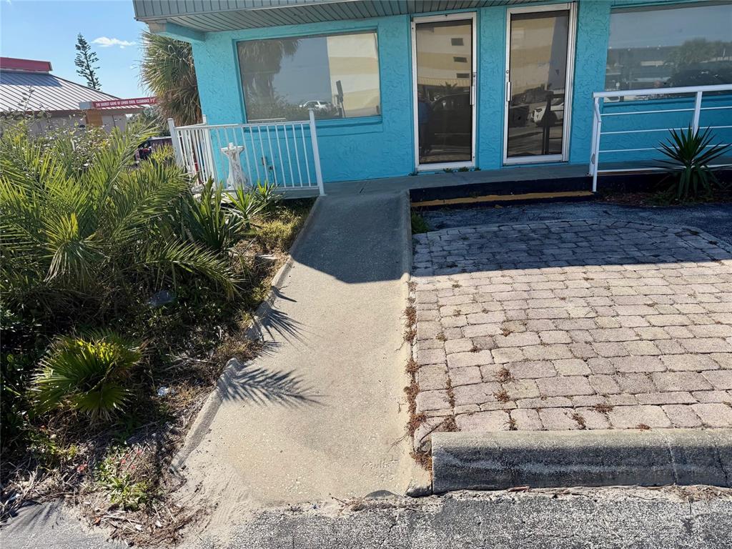 A concrete wheelchair ramp leads to the entrance of a blue building with glass doors — 3400 S ATLANTIC AVENUE UNIT 3416, DAYTONA BEACH, FL