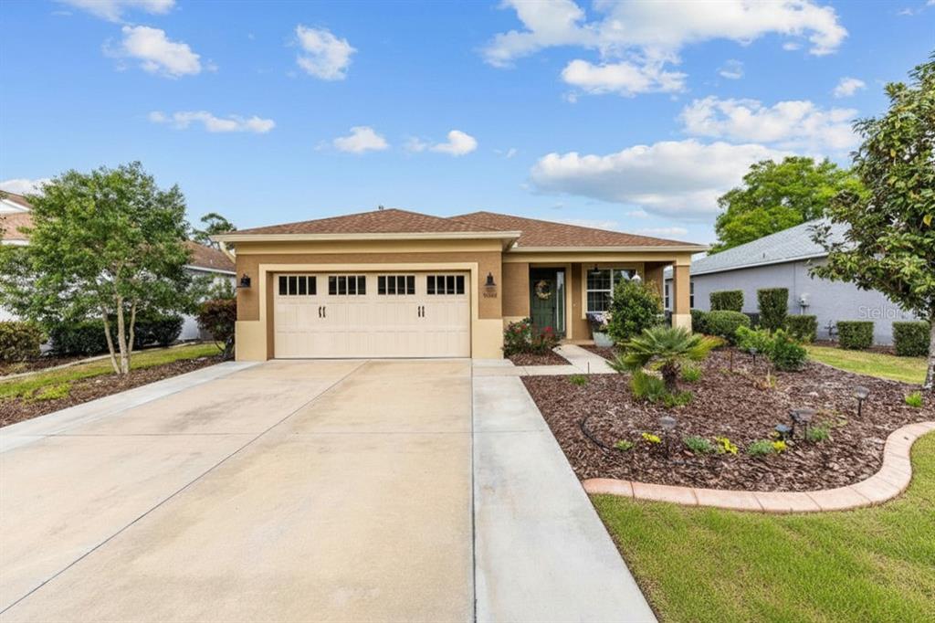 A single-story house with a tan stucco exterior, a two-car garage, and a landscaped yard — 8566 SW 79TH AVENUE, OCALA, FL